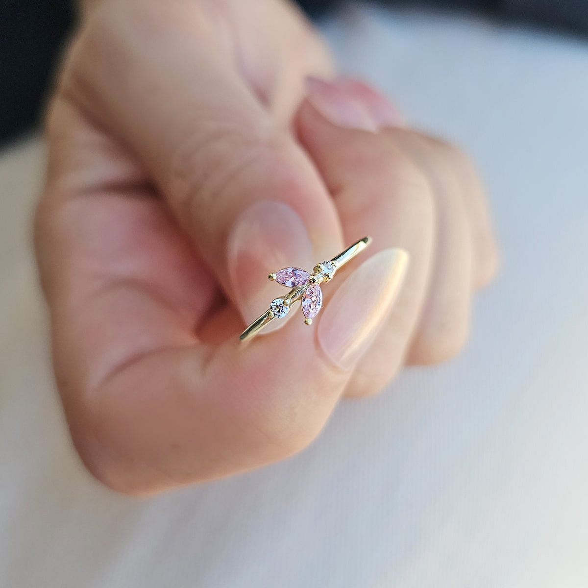 Gold pink-stone marquise leaf ring on raised hand