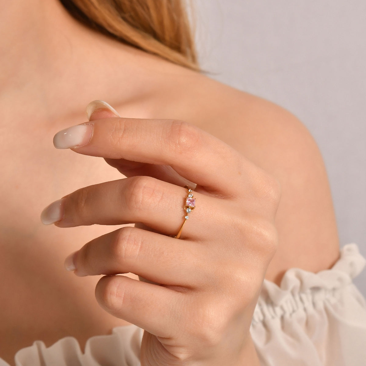 10K gold pink-stone princess diamond ring on finger, close-up