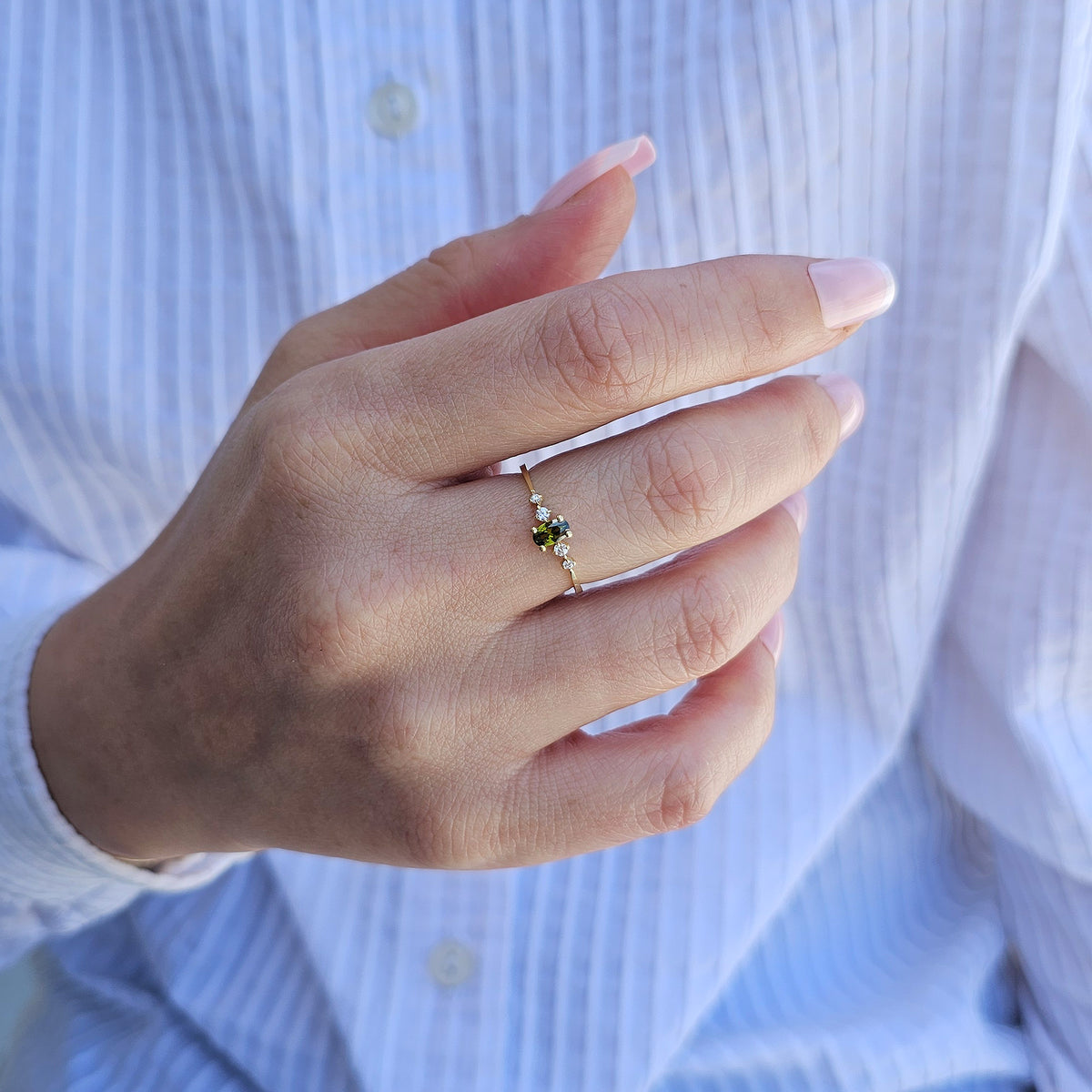 Gold green-stone oval ring on raised hand