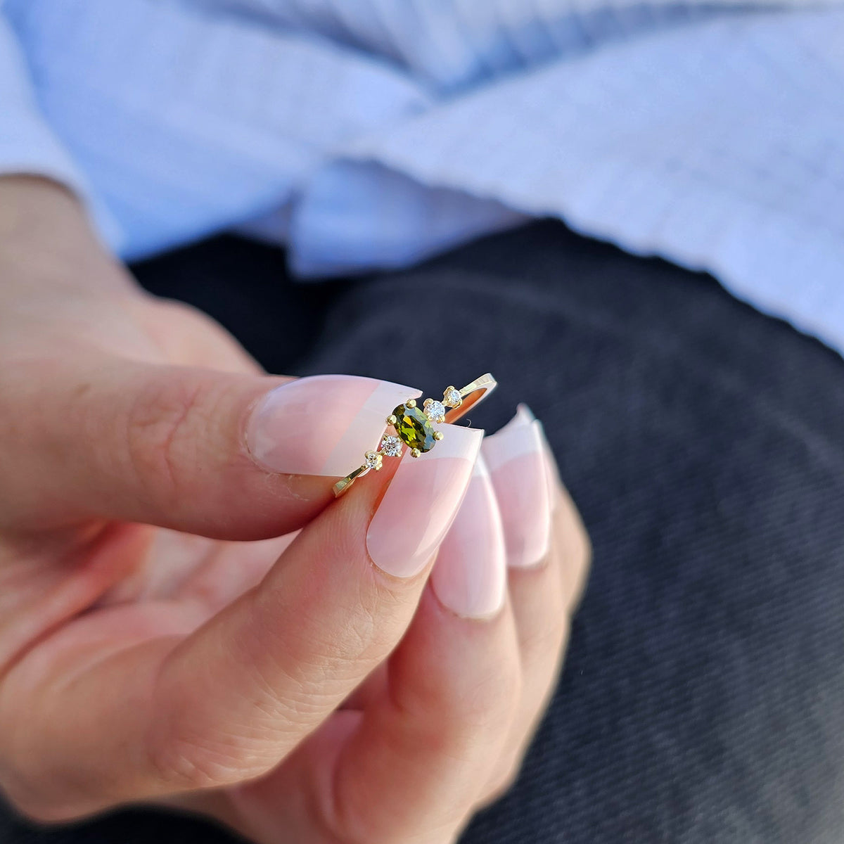 Gold green-stone oval ring on finger, close-up