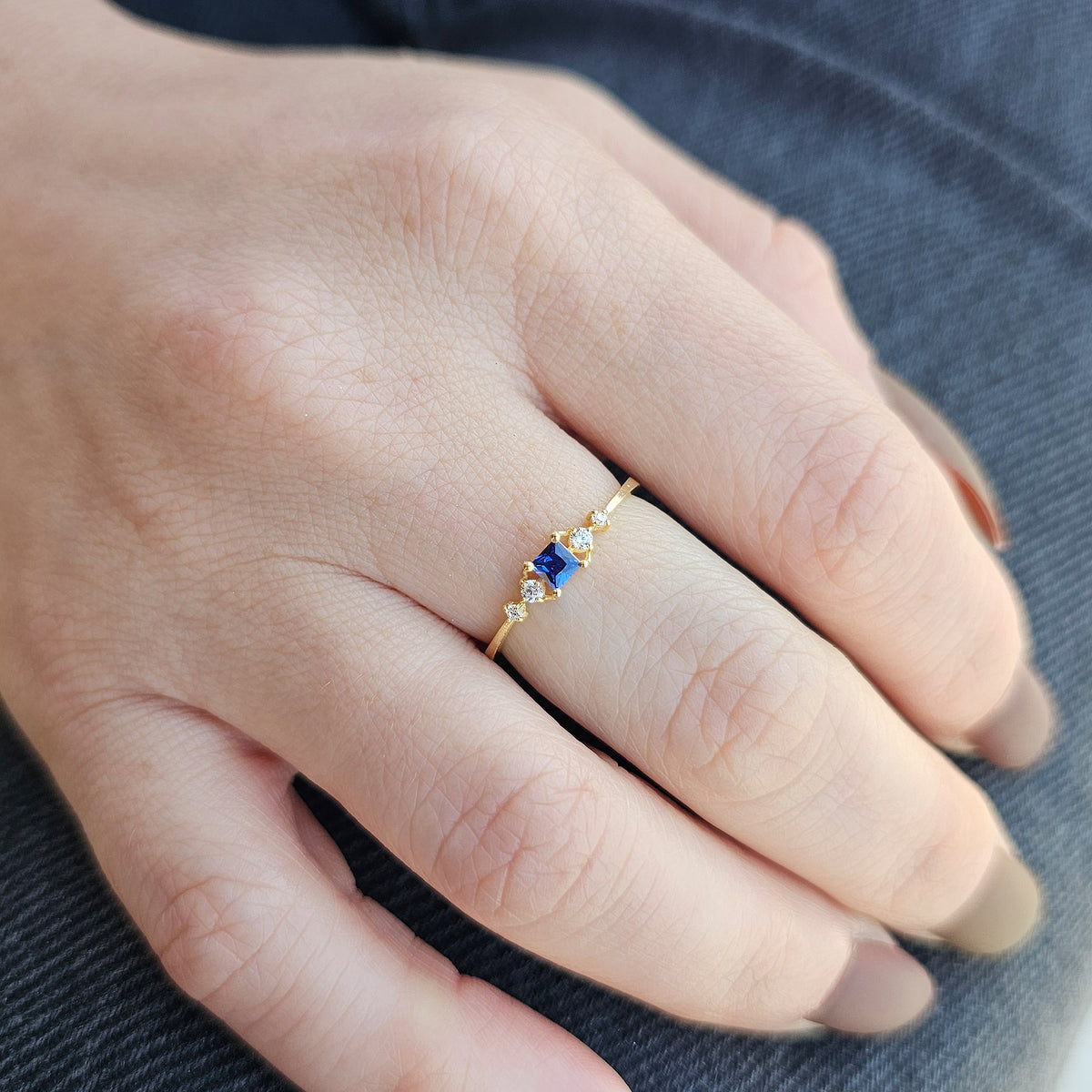 Gold blue-stone princess ring worn on hand, close-up