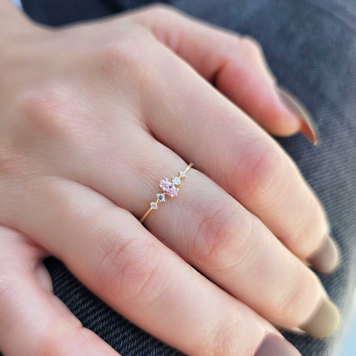 Gold pink-stone marquise ring worn on hand, close-up