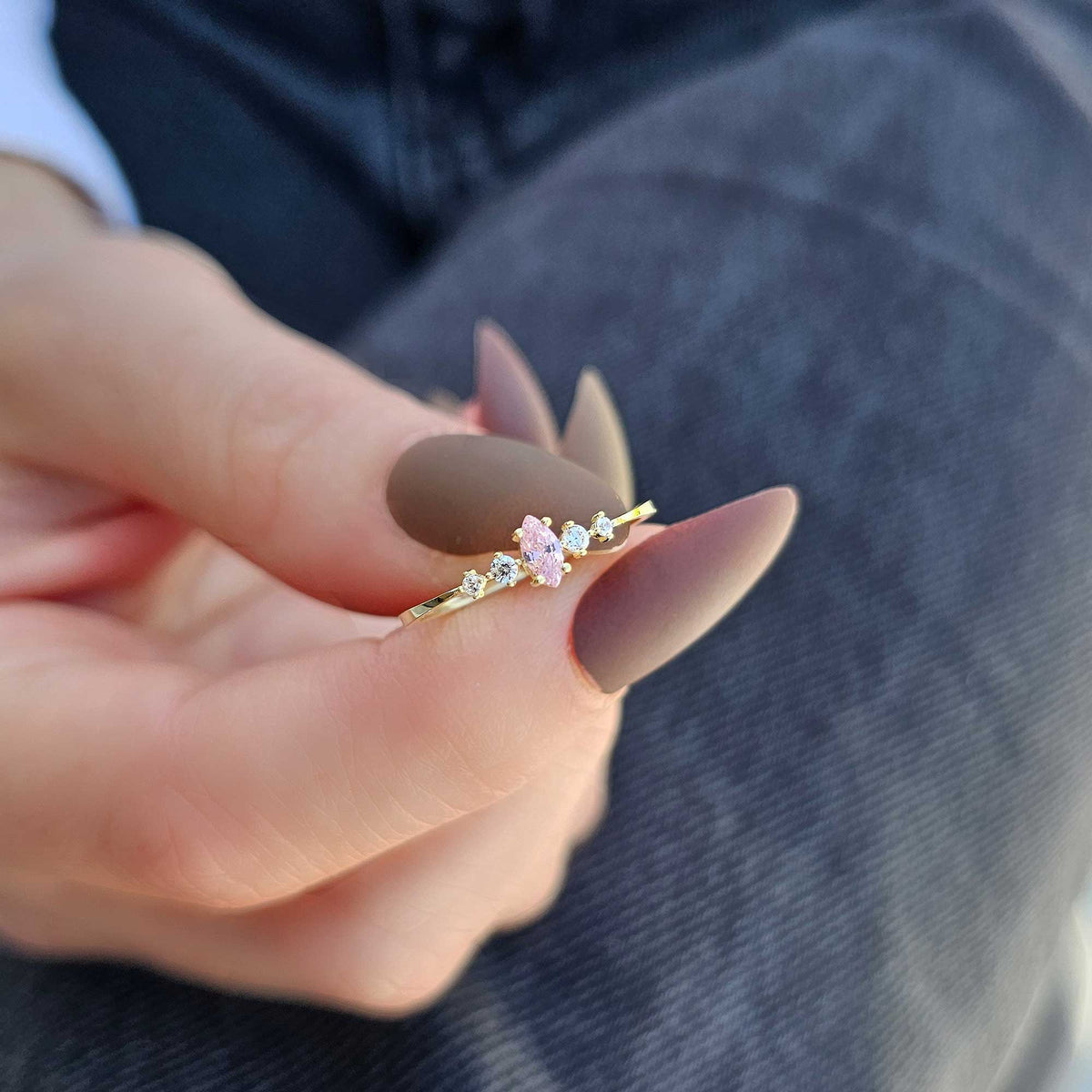 Gold pink-stone marquise ring on raised hand