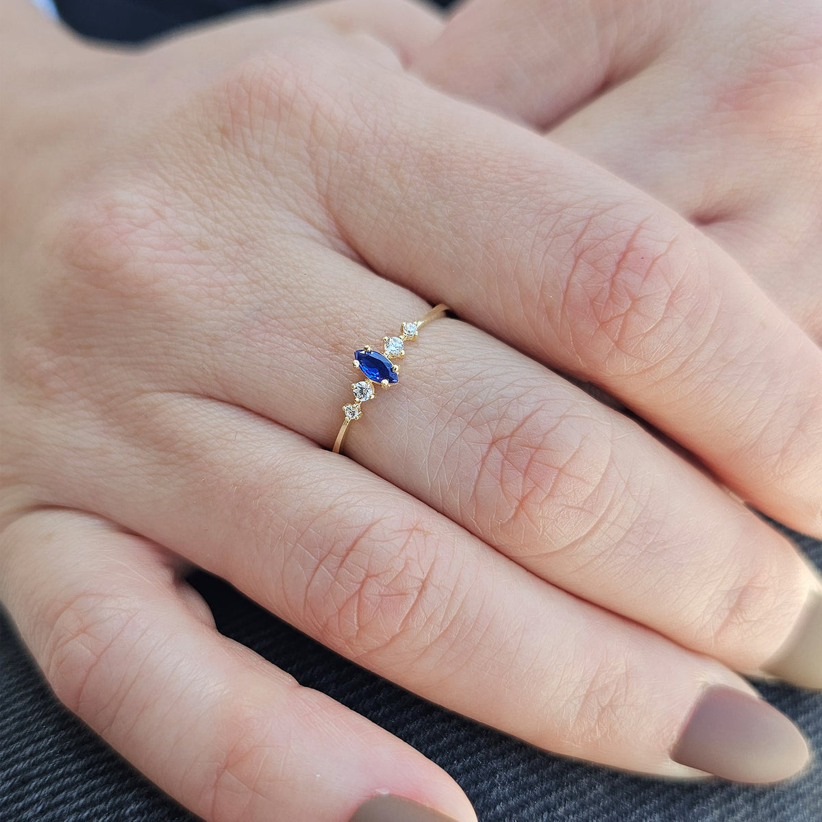 Gold blue-stone marquise ring worn on hand, close-up