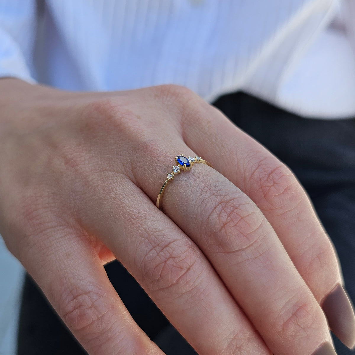 Gold blue-stone marquise ring worn on hand, side view