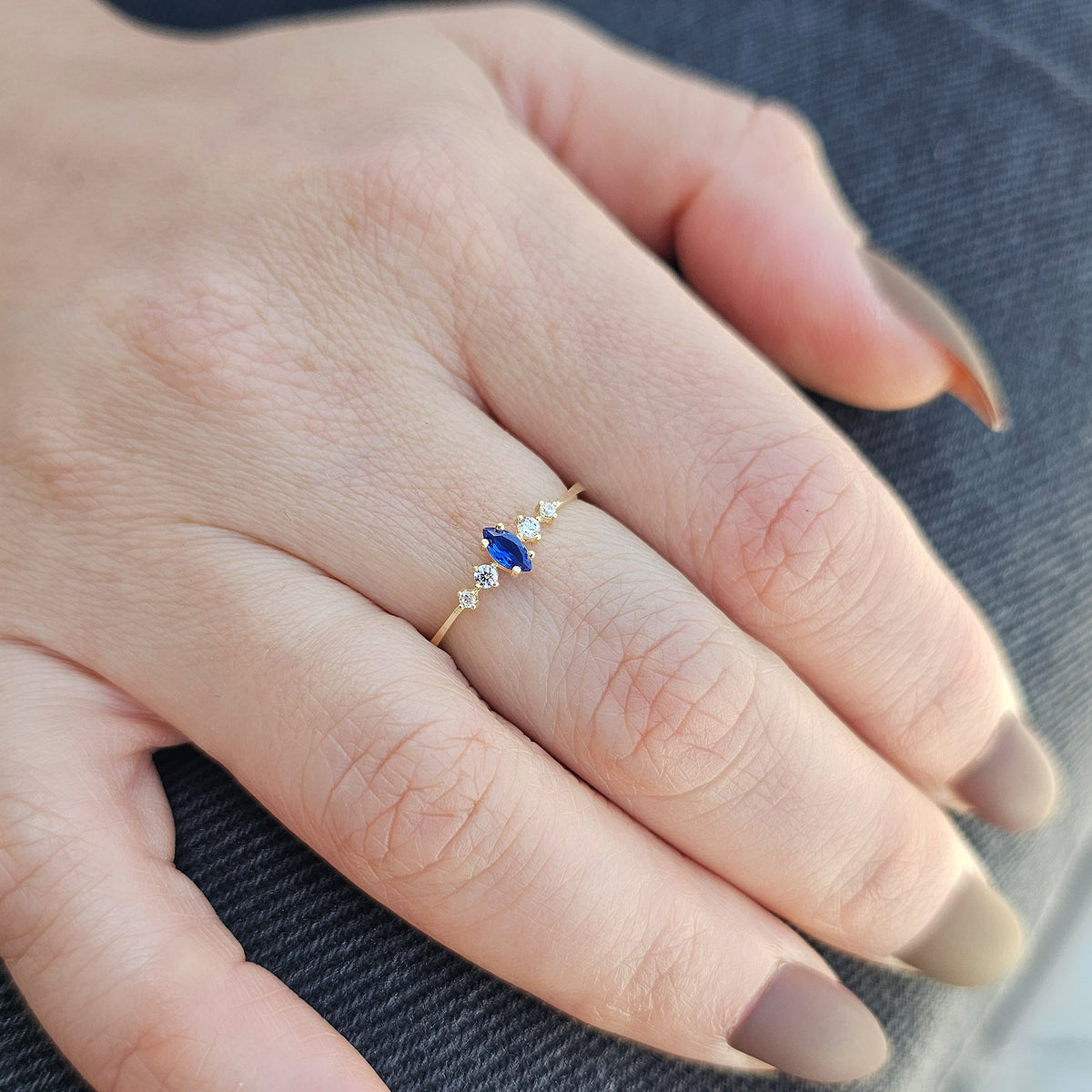 Gold blue-stone marquise ring worn on hand