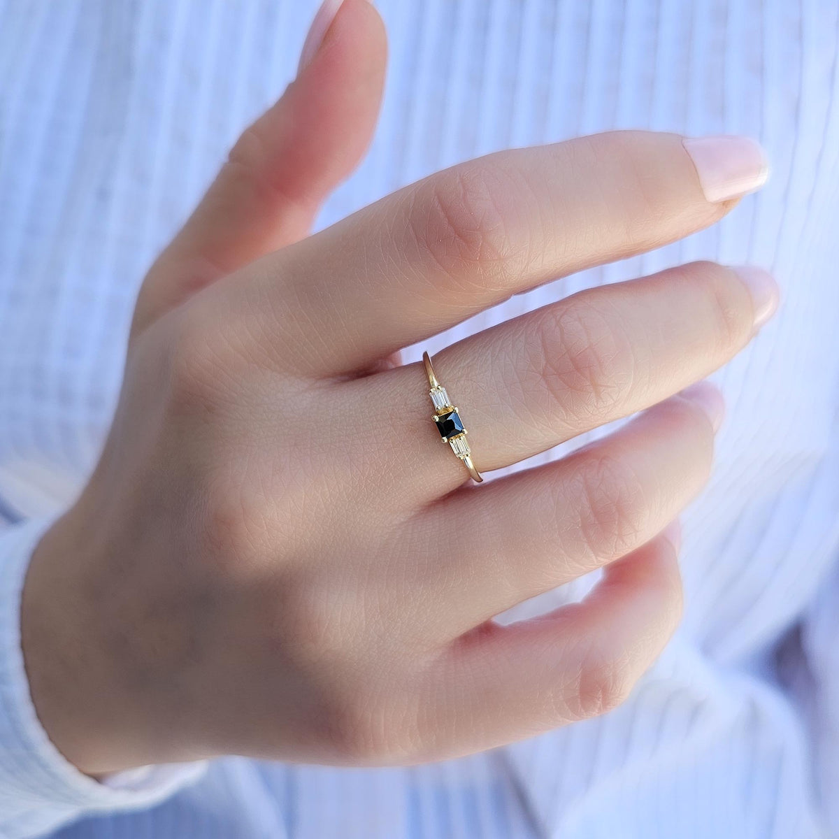 Gold black-stone baguette ring worn on hand, close-up