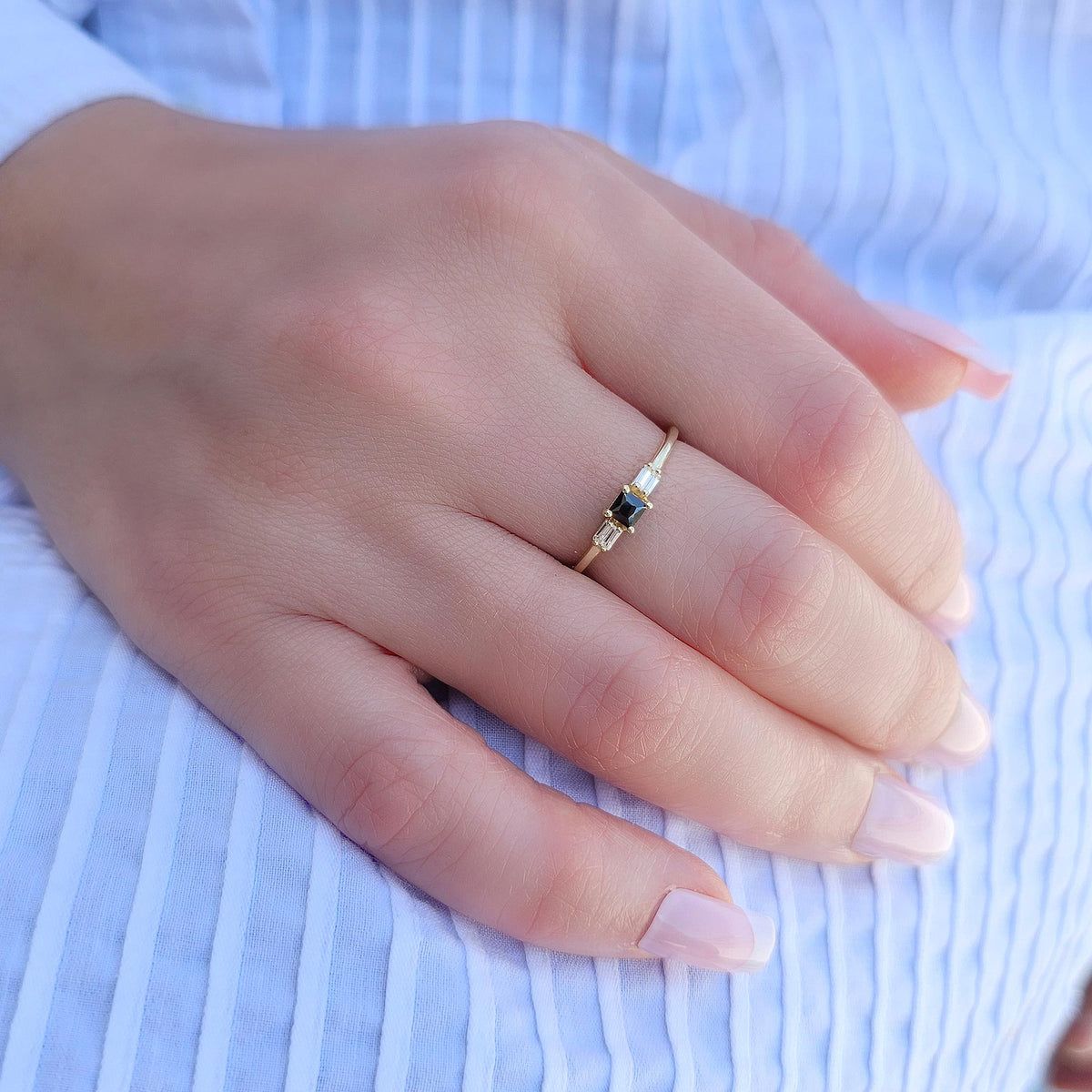 Gold black-stone baguette ring worn on hand, side view