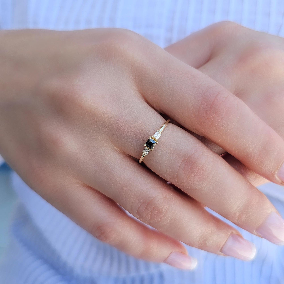 Gold black-stone baguette ring worn on hand