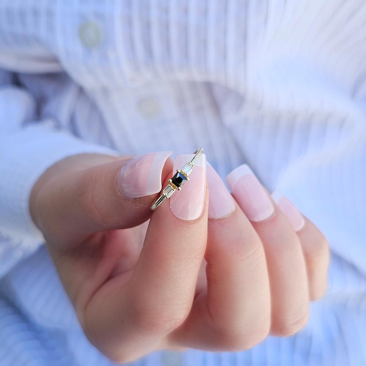 Gold black-stone baguette ring on raised hand
