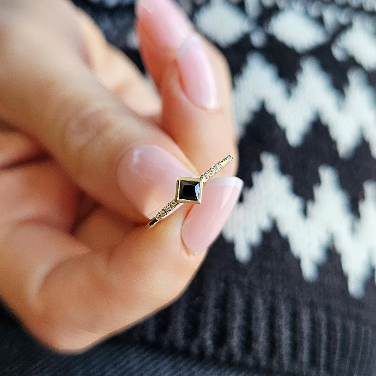 Gold black-stone princess ring on raised hand
