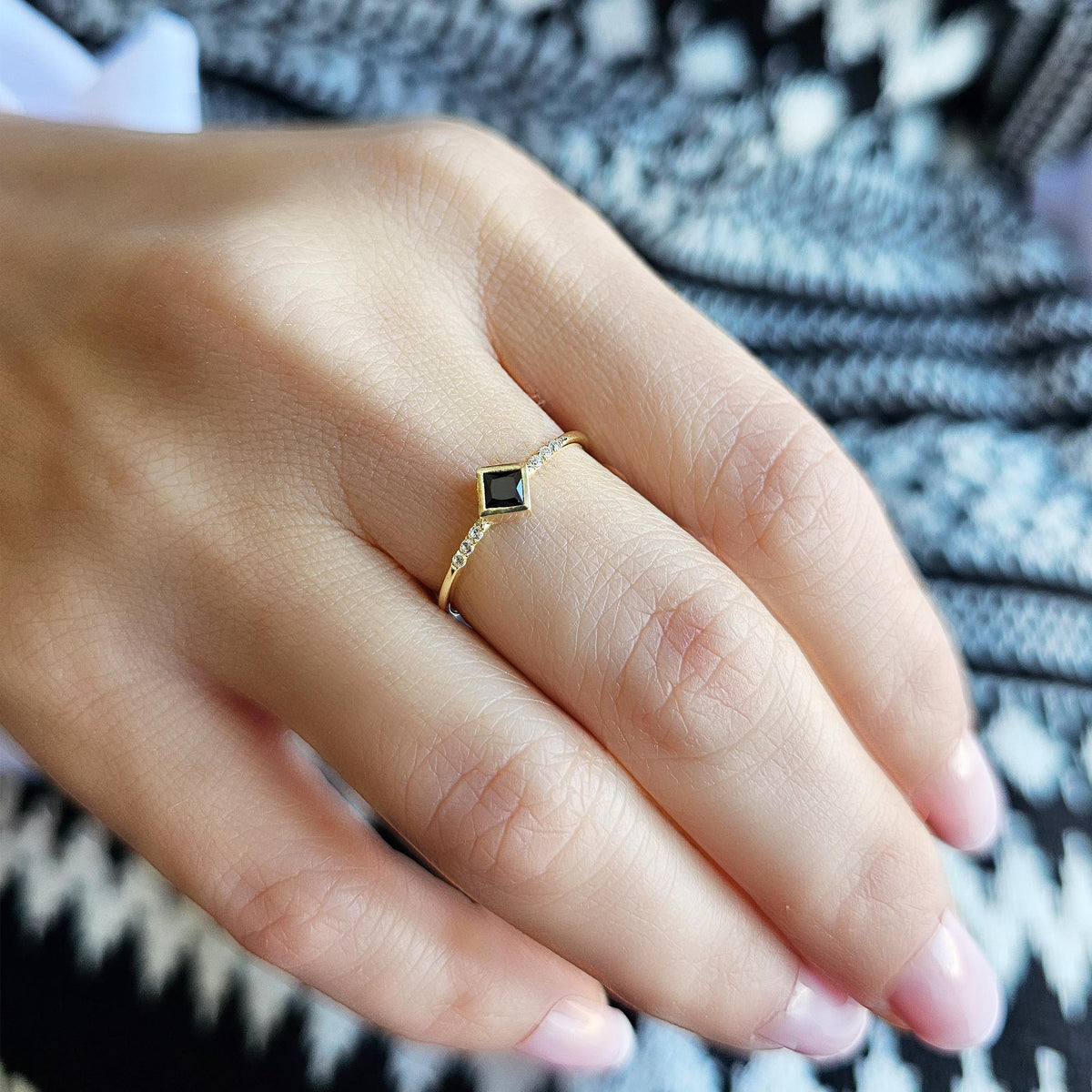 Gold black-stone princess ring worn on hand, side view