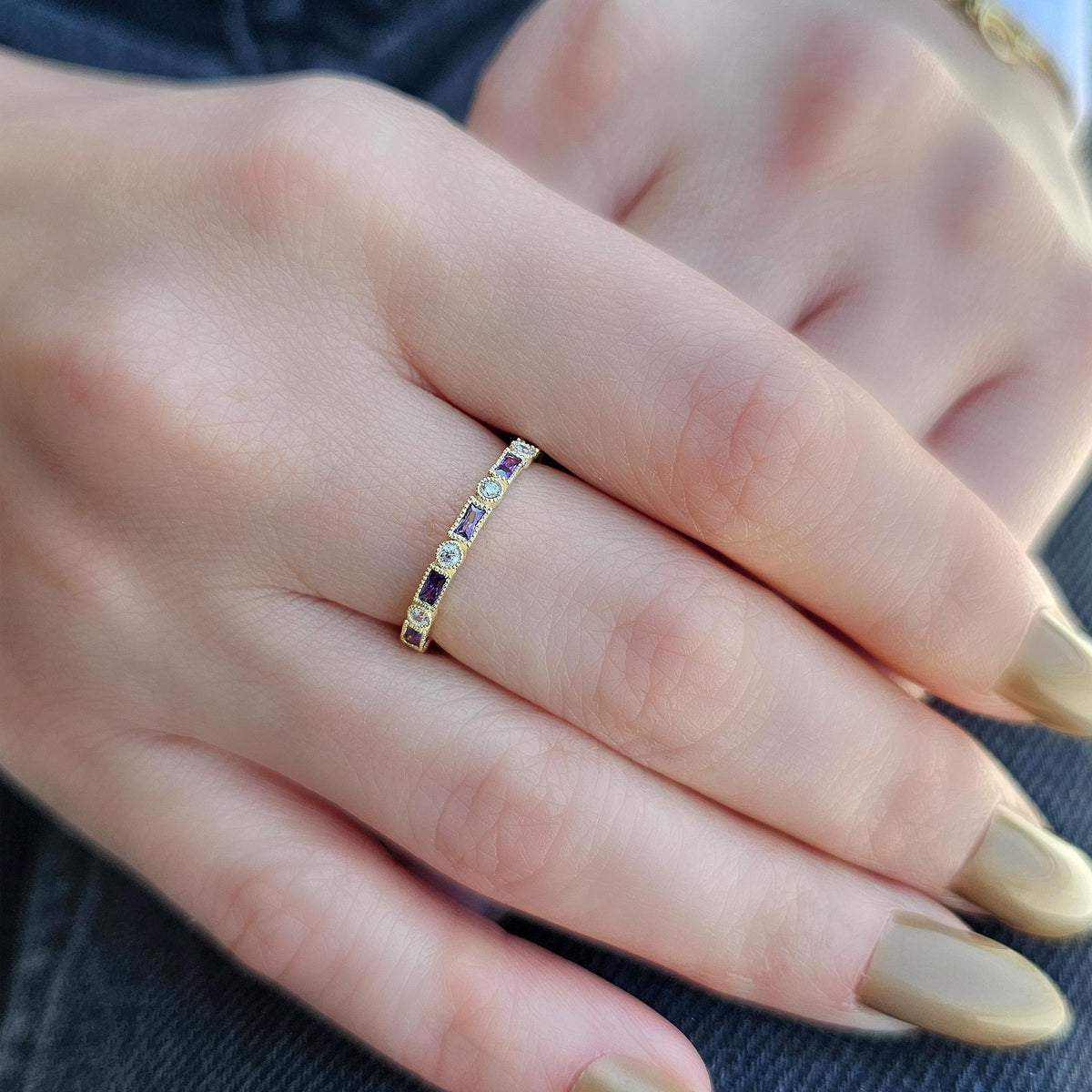 Gold purple-stone baguette ring worn on hand, side view