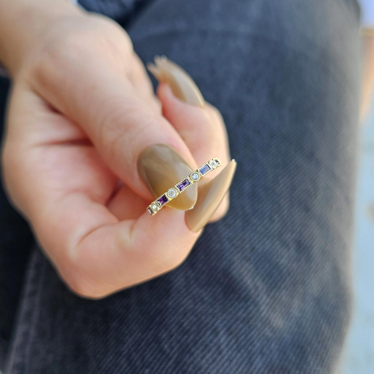 Gold purple-stone baguette ring worn on hand, close-up