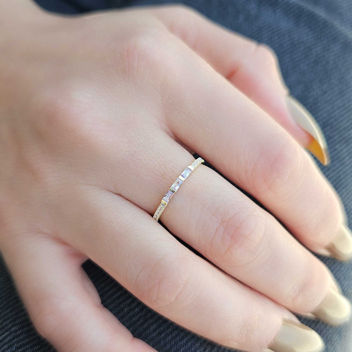 Gold lavender-stone baguette ring worn on hand, side view