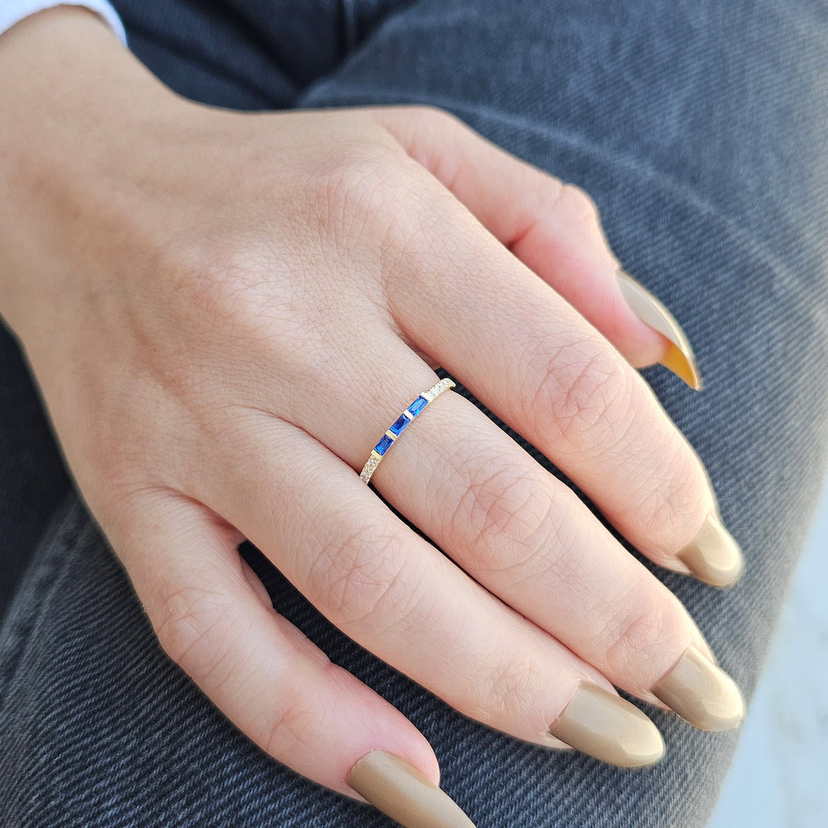 Gold blue-stone baguette ring worn on hand