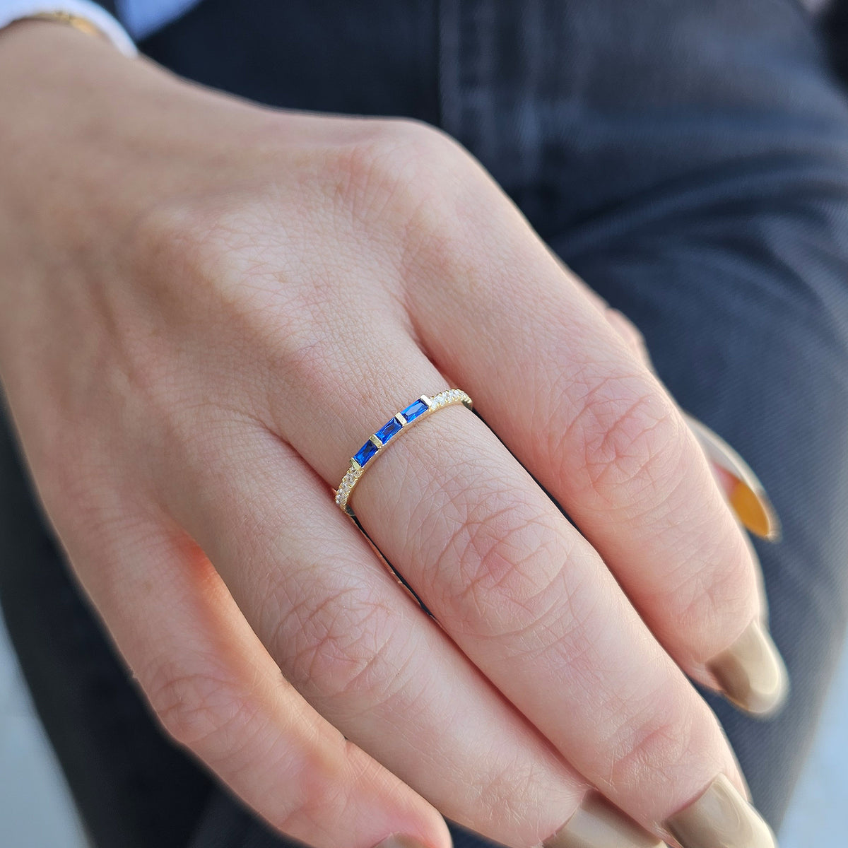 Gold blue-stone baguette ring on raised hand