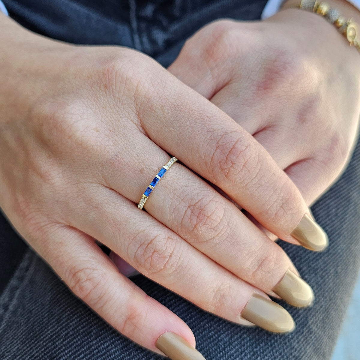 Gold blue-stone baguette ring worn on hand, side view