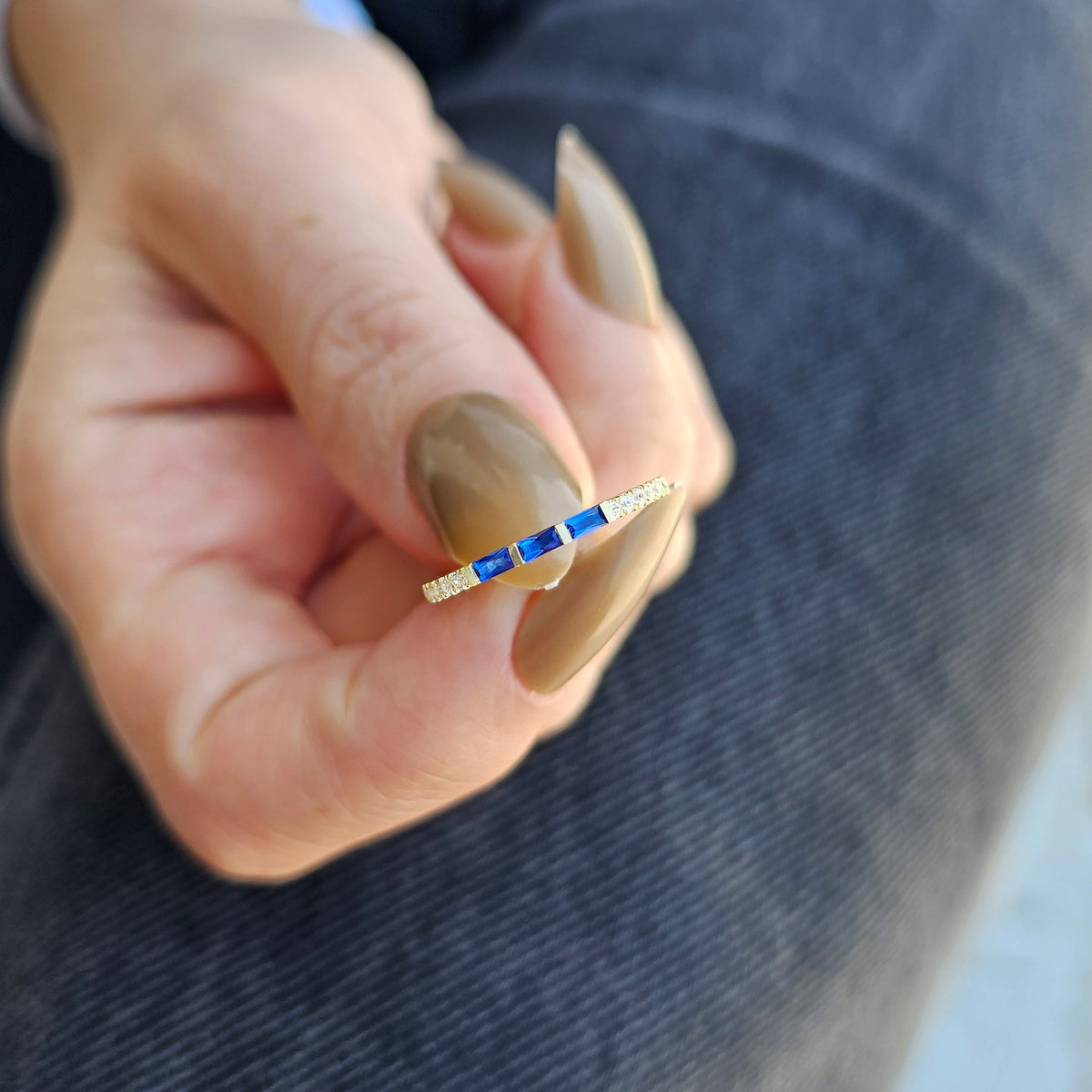 Gold blue-stone baguette ring worn on hand, close-up