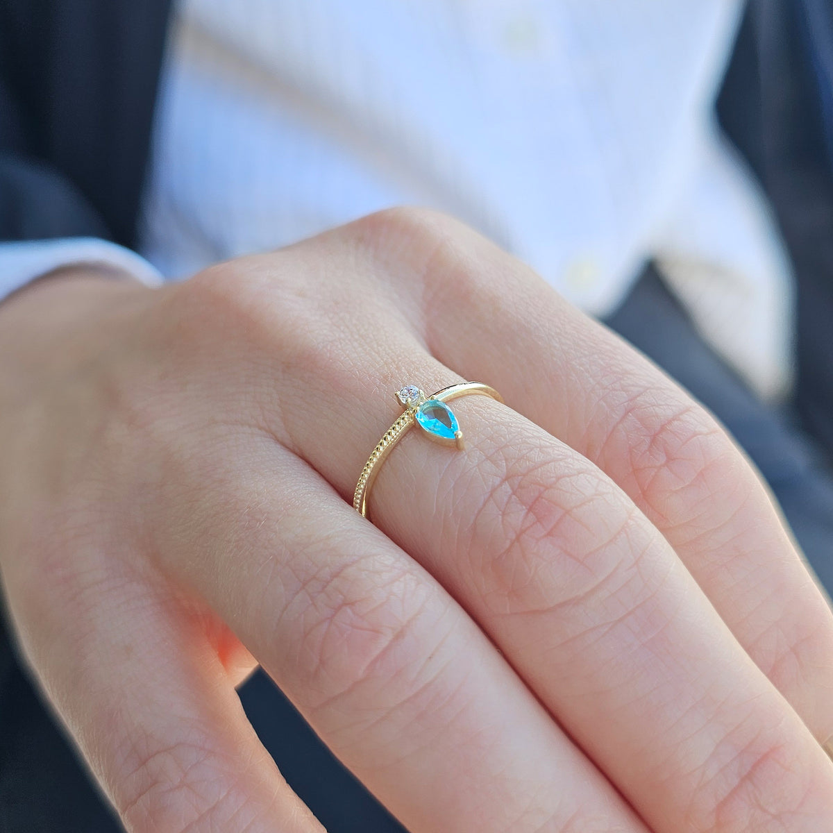 Gold aqua-blue-stone pear ring worn on hand, side view
