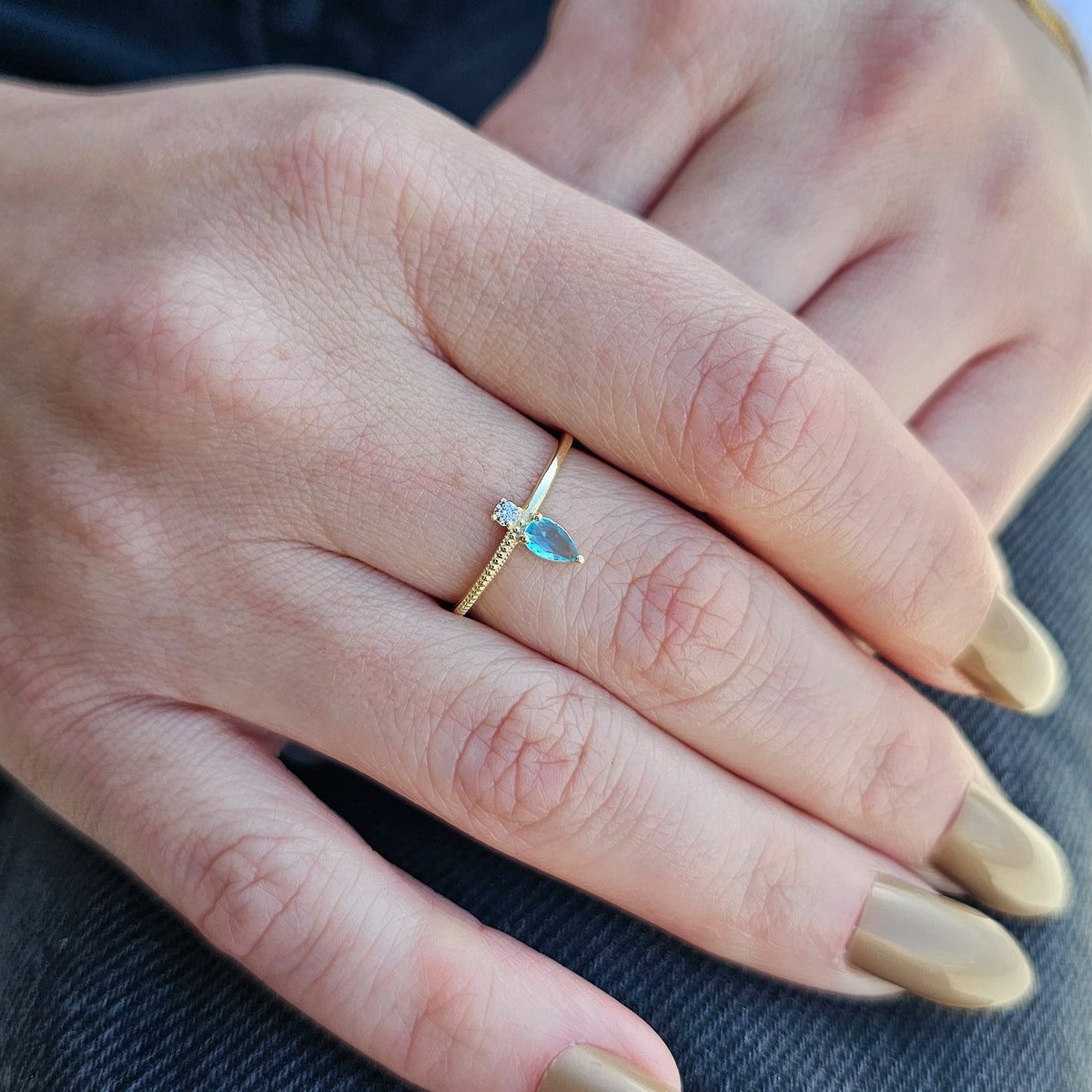 Gold aqua-blue-stone pear ring worn on hand