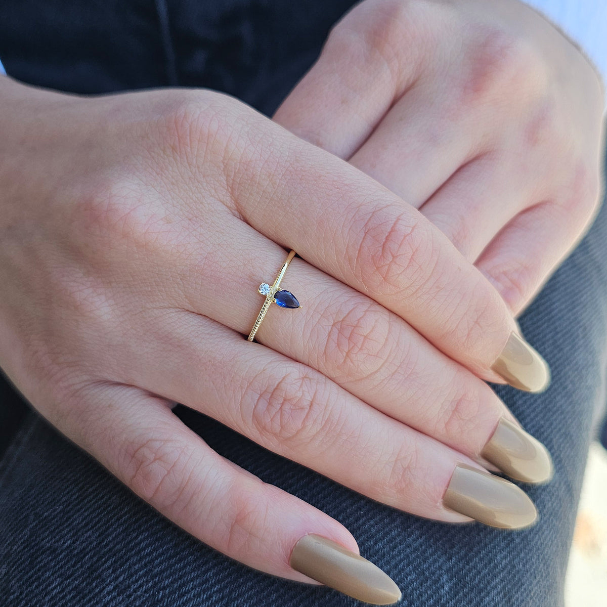 Gold blue-stone pear ring on raised hand