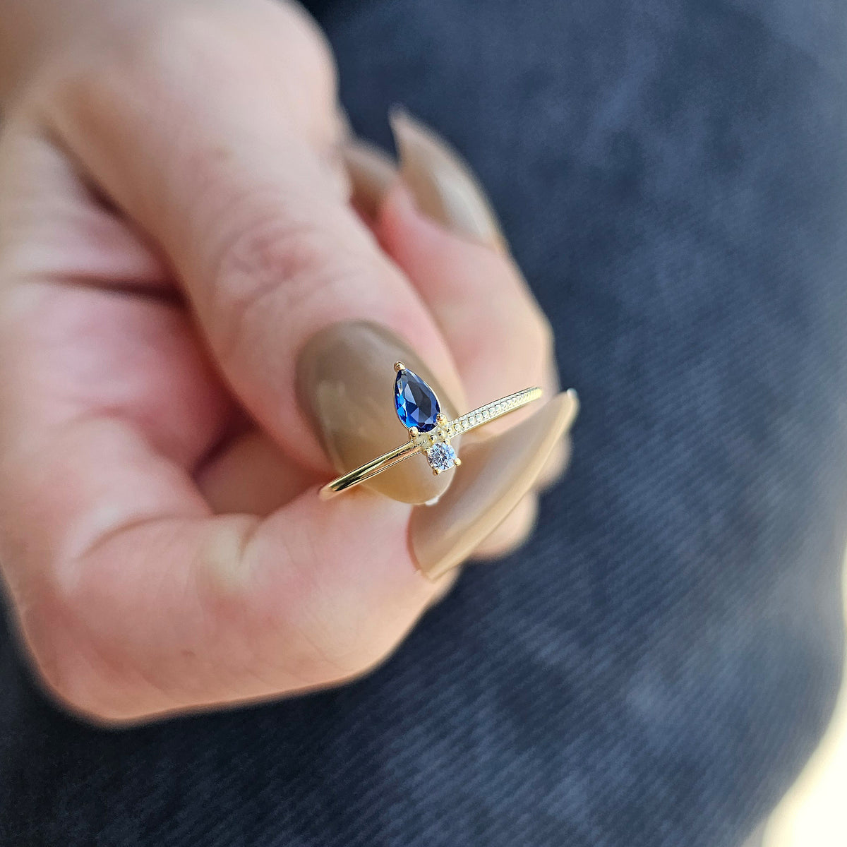 Gold blue-stone pear ring worn on hand, close-up