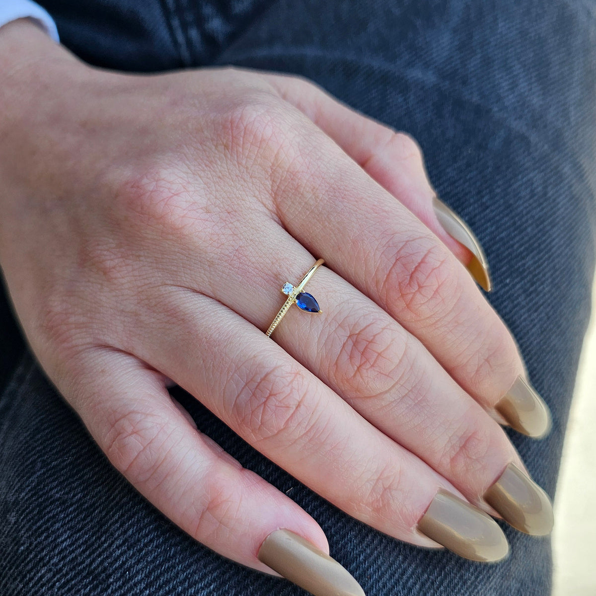 Gold blue-stone pear ring worn on hand, side view