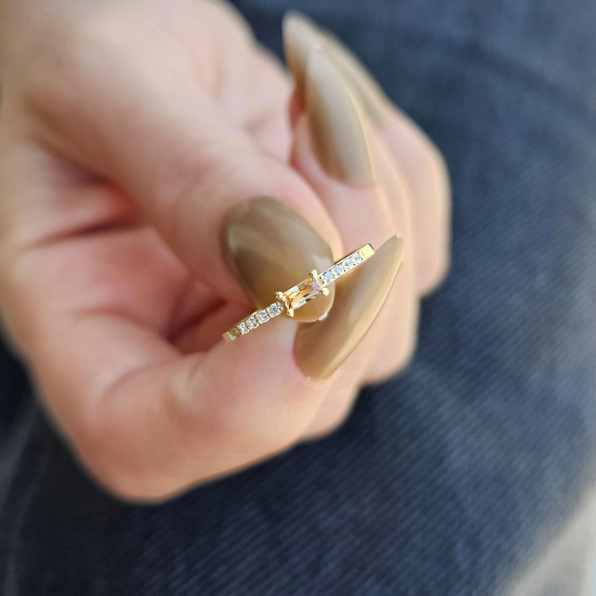 Gold champagne-stone baguette ring on raised hand