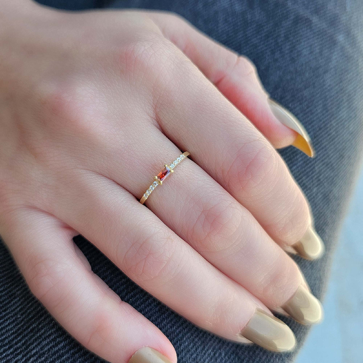 Gold dark-red-stone baguette ring worn on hand