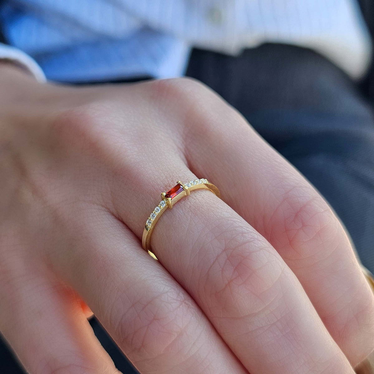 Gold dark-red-stone baguette ring worn on hand, side view