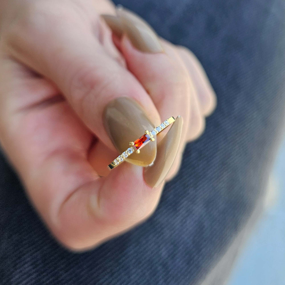 Gold dark-red-stone baguette ring worn on hand, close-up