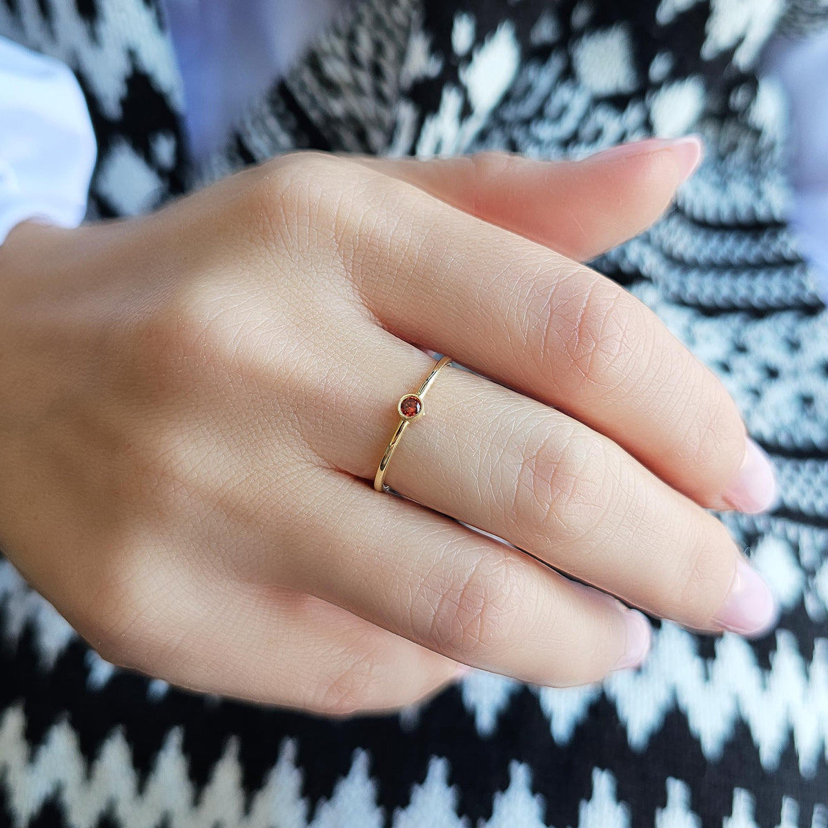 Gold dark-red-stone bezel solitaire ring worn on hand