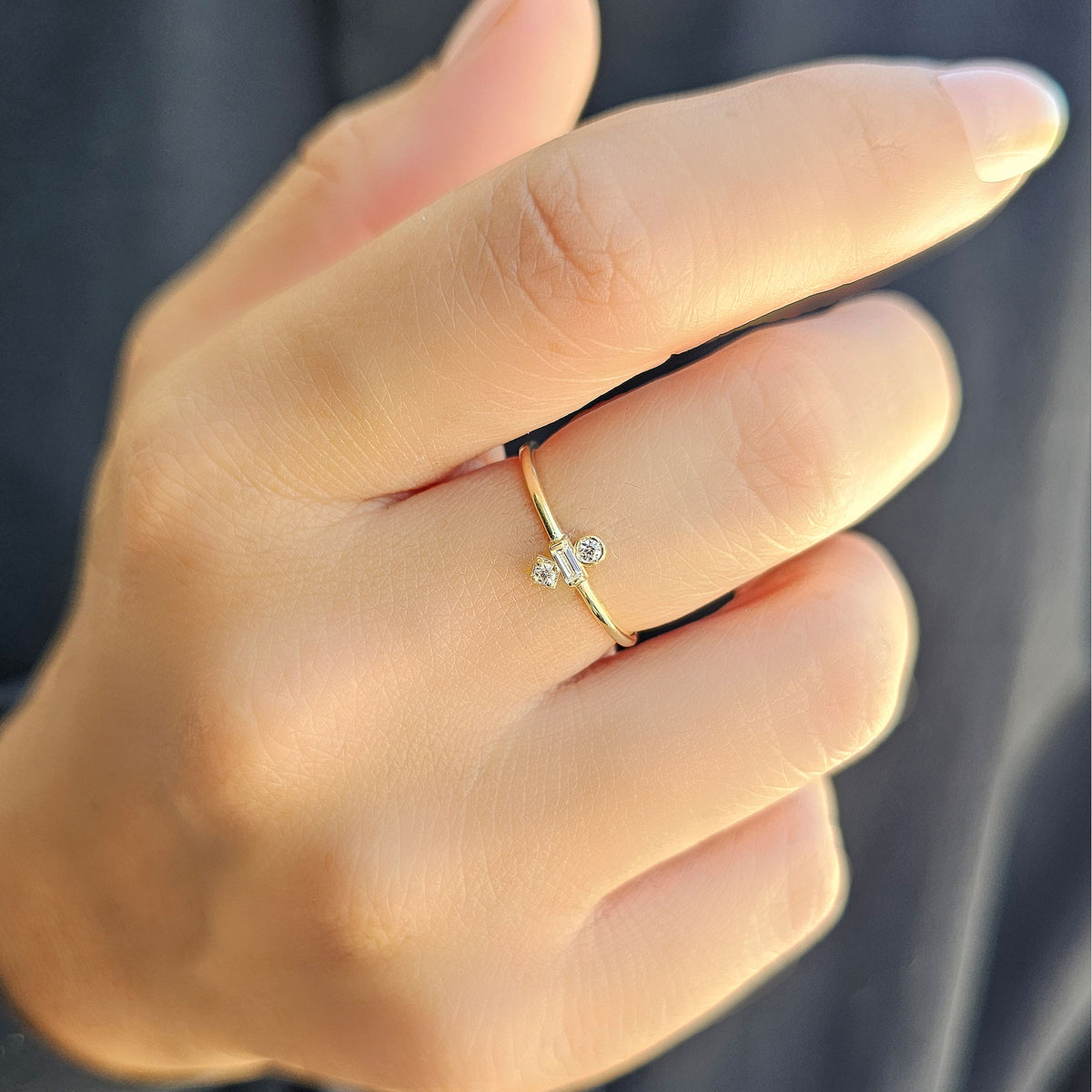 Gold three-stone baguette ring worn on hand, close-up