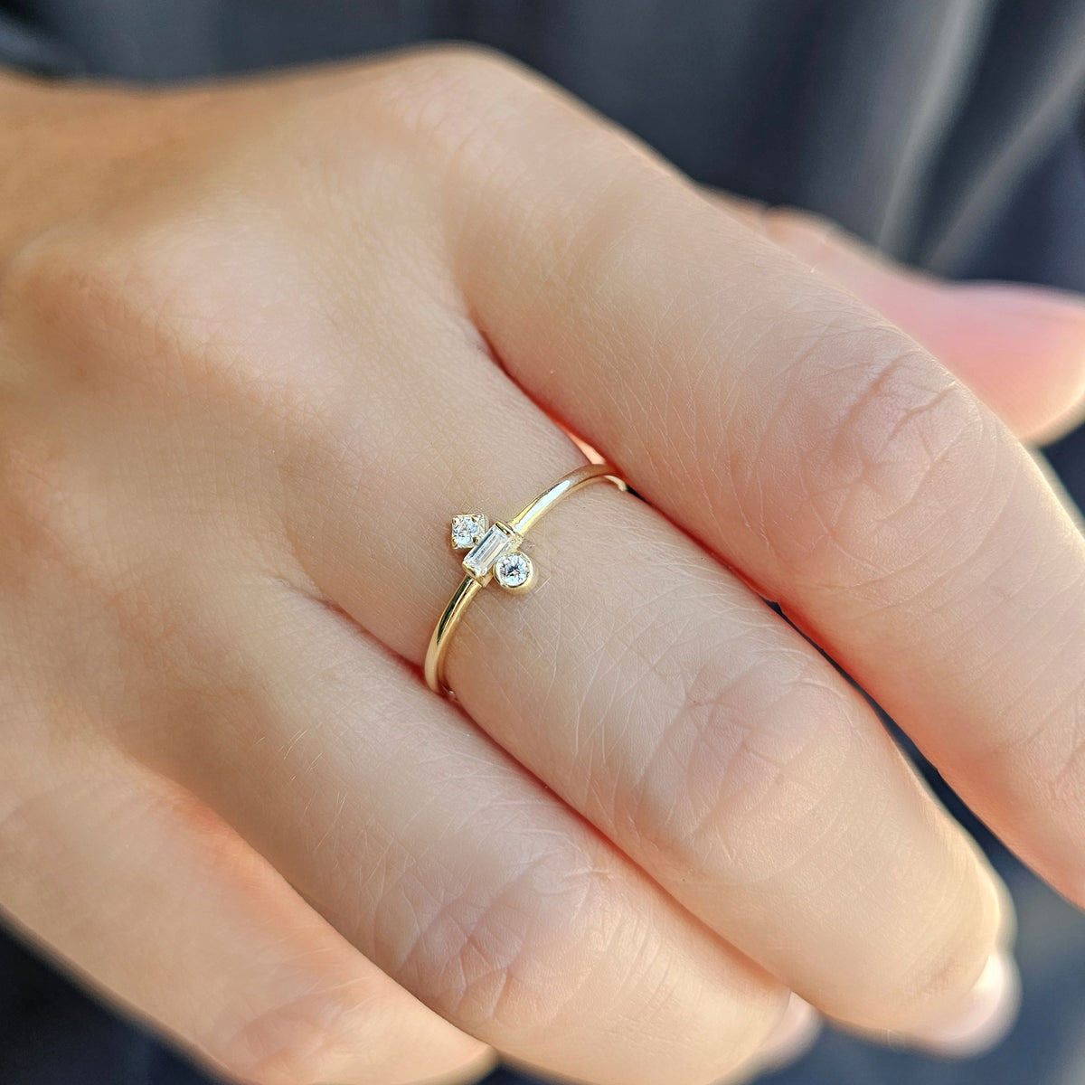 Gold three-stone baguette ring worn on hand, side view