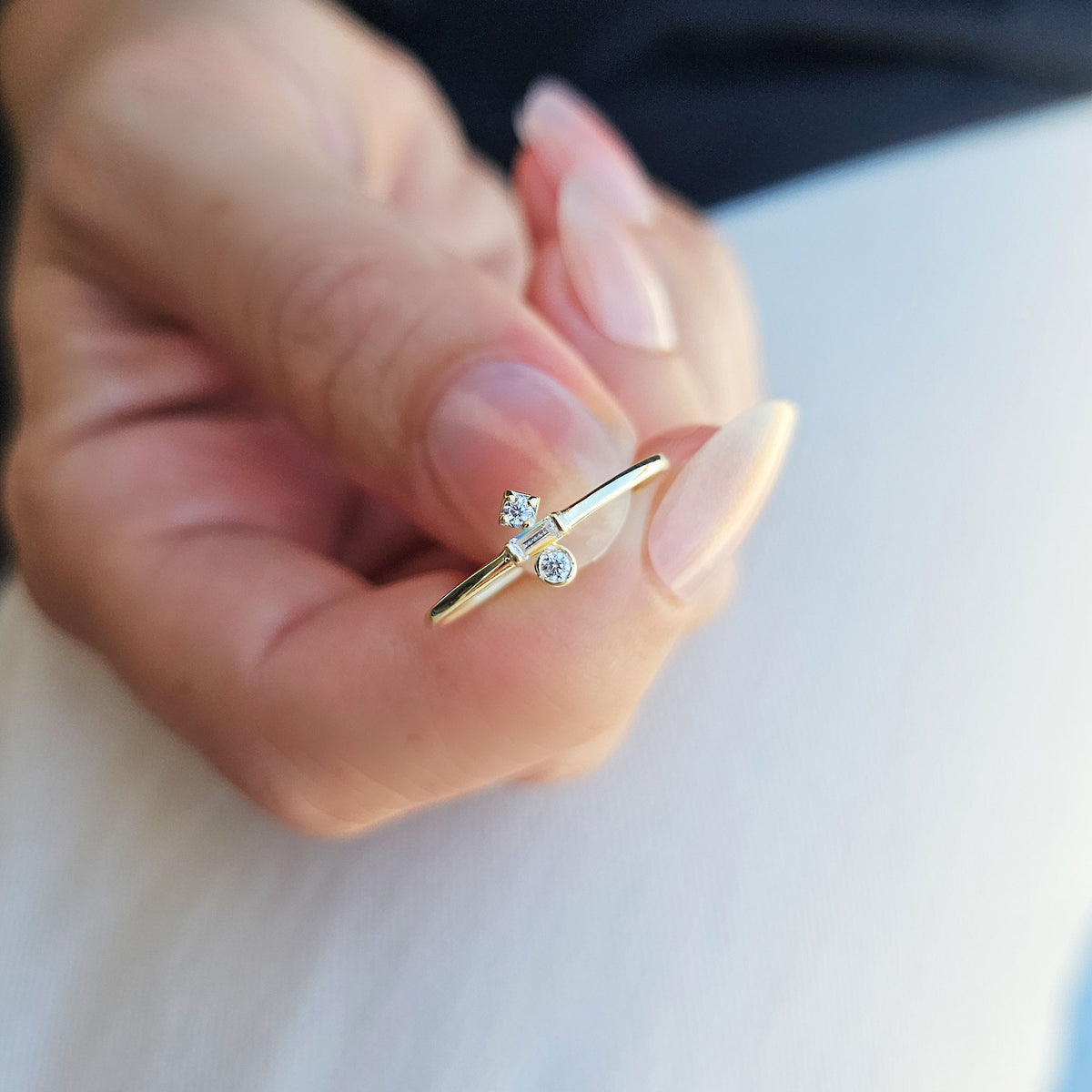 Gold three-stone baguette ring on raised hand