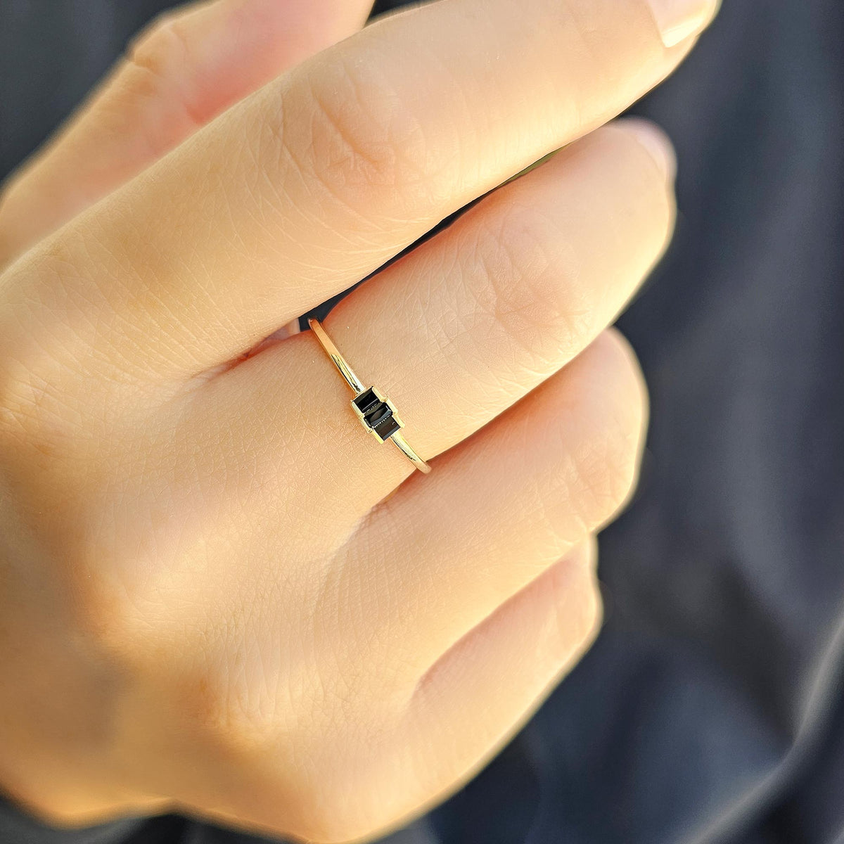 Gold black onyx three-baguette ring worn on hand, close-up