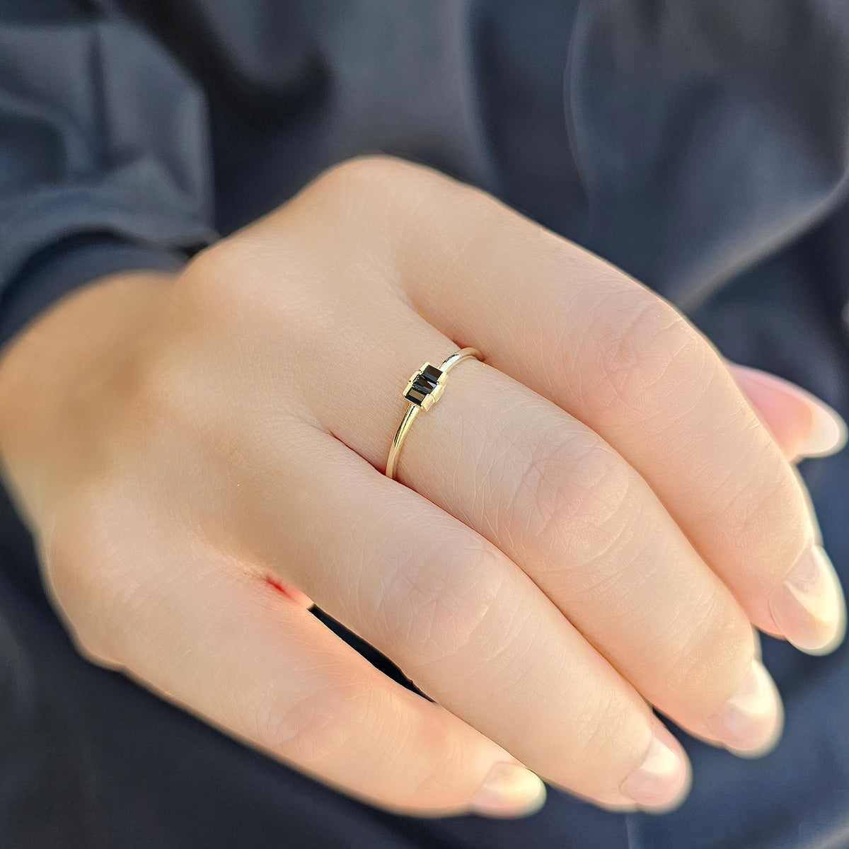 Gold black onyx three-baguette ring worn on hand, side view