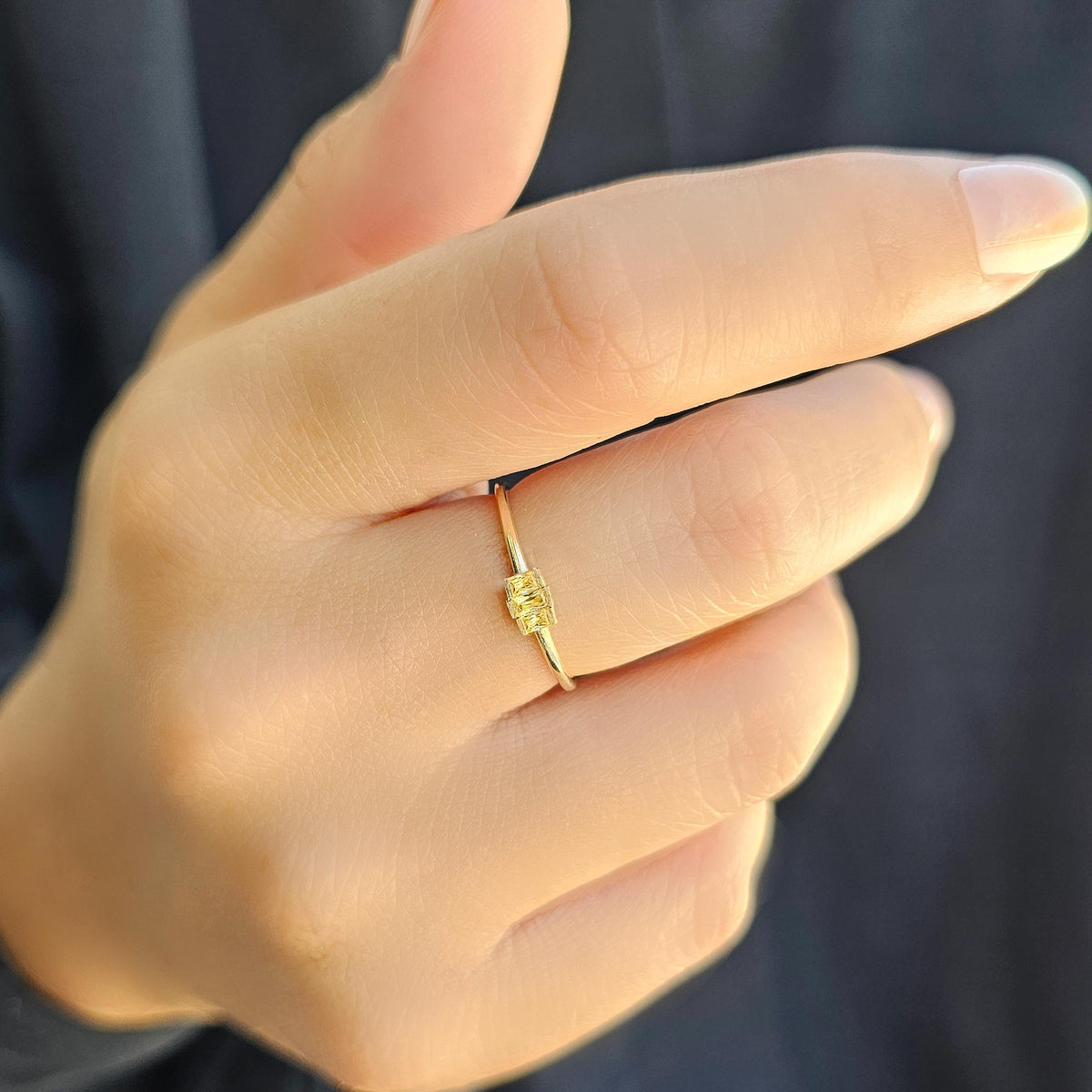 Gold yellow-stone three-baguette ring worn on hand