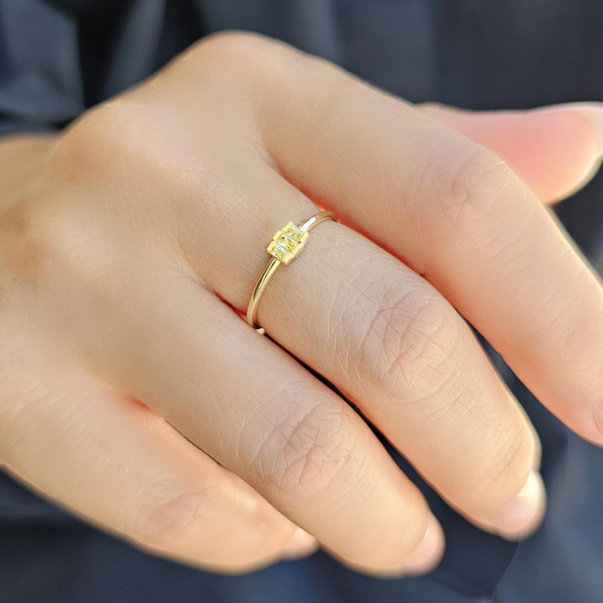Gold yellow-stone three-baguette ring worn on hand, close-up