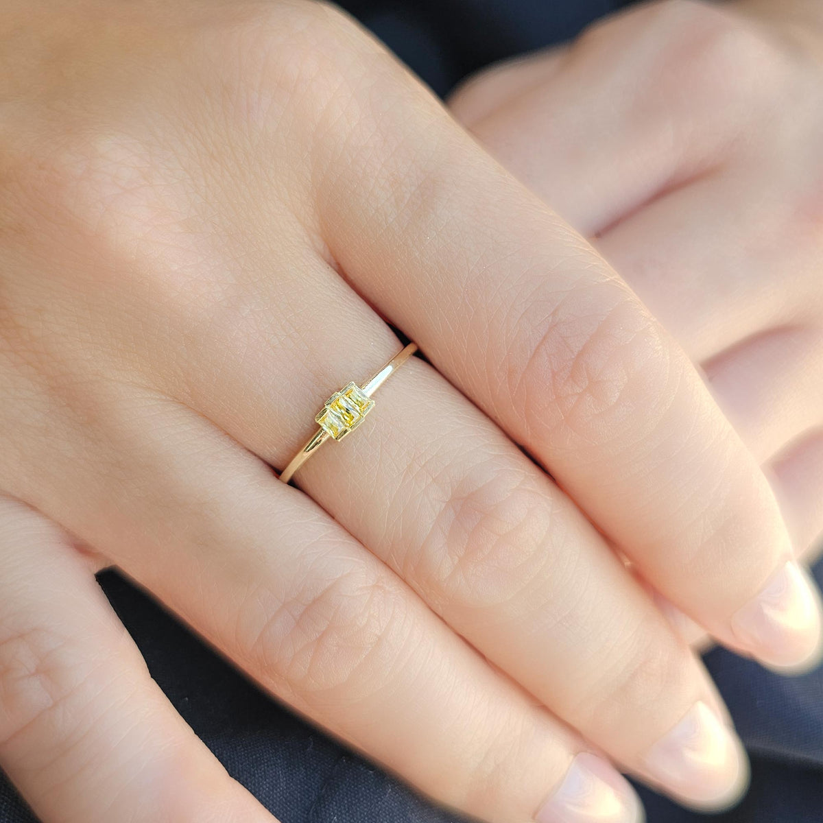 Gold yellow-stone three-baguette ring worn on hand, side view