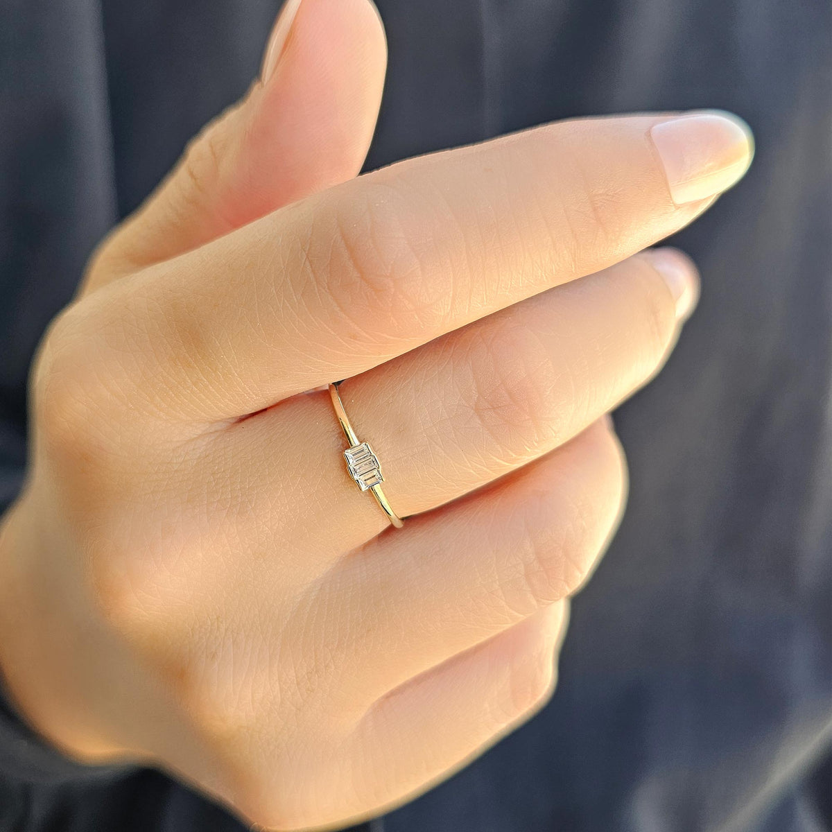 Gold white-stone three-baguette ring worn on hand, close-up