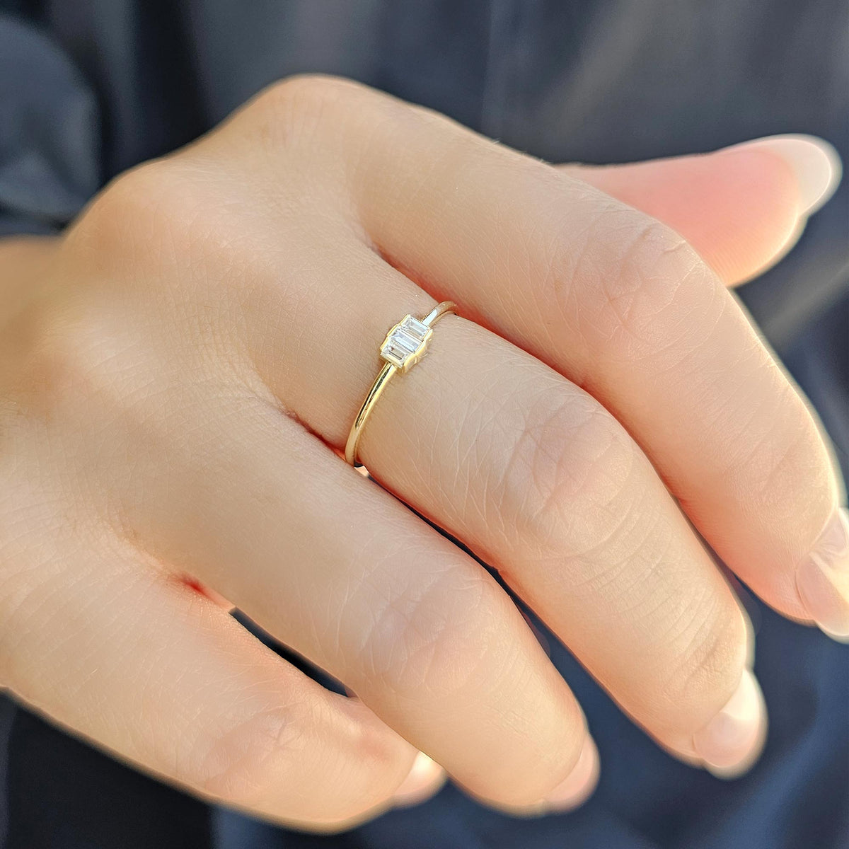 Gold white-stone three-baguette ring worn on hand, side view