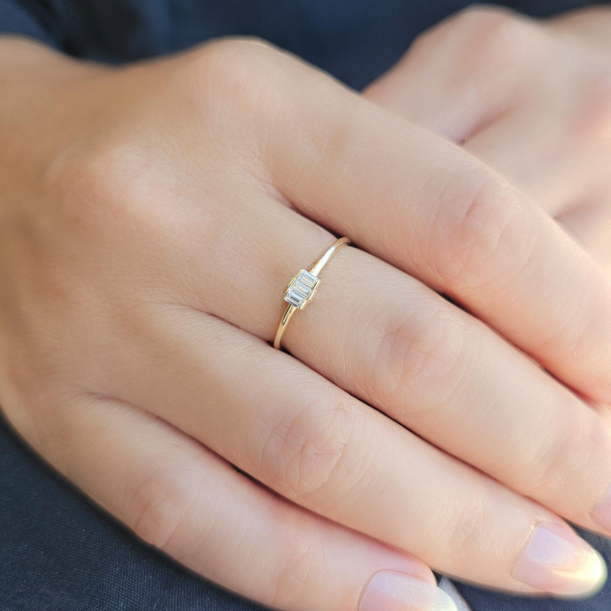 Gold white-stone three-baguette ring worn on hand