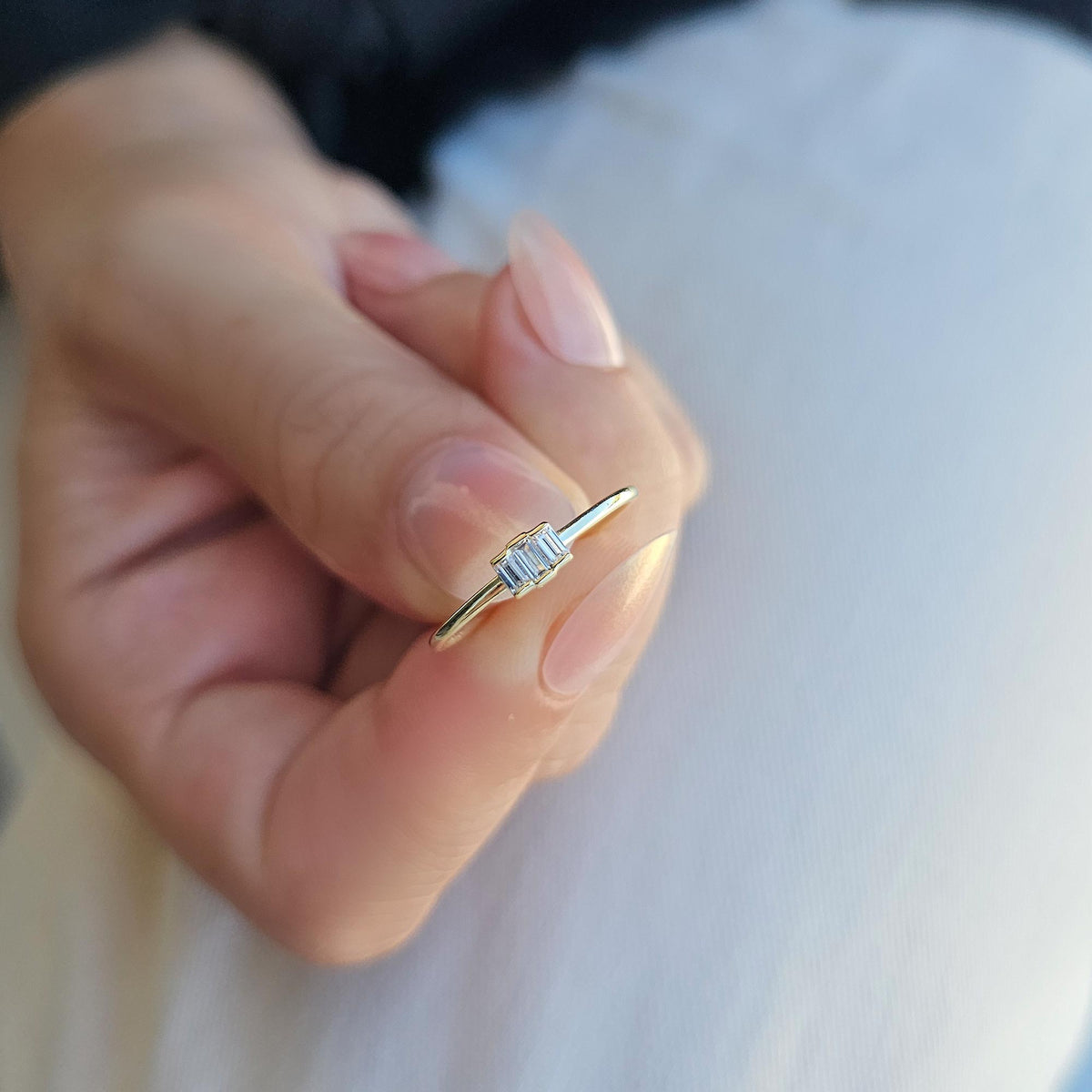 Gold white-stone three-baguette ring on raised hand