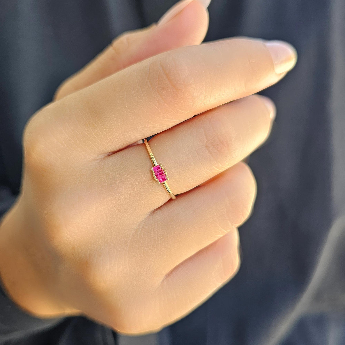 Gold red-stone three-baguette ring worn on hand, close-up