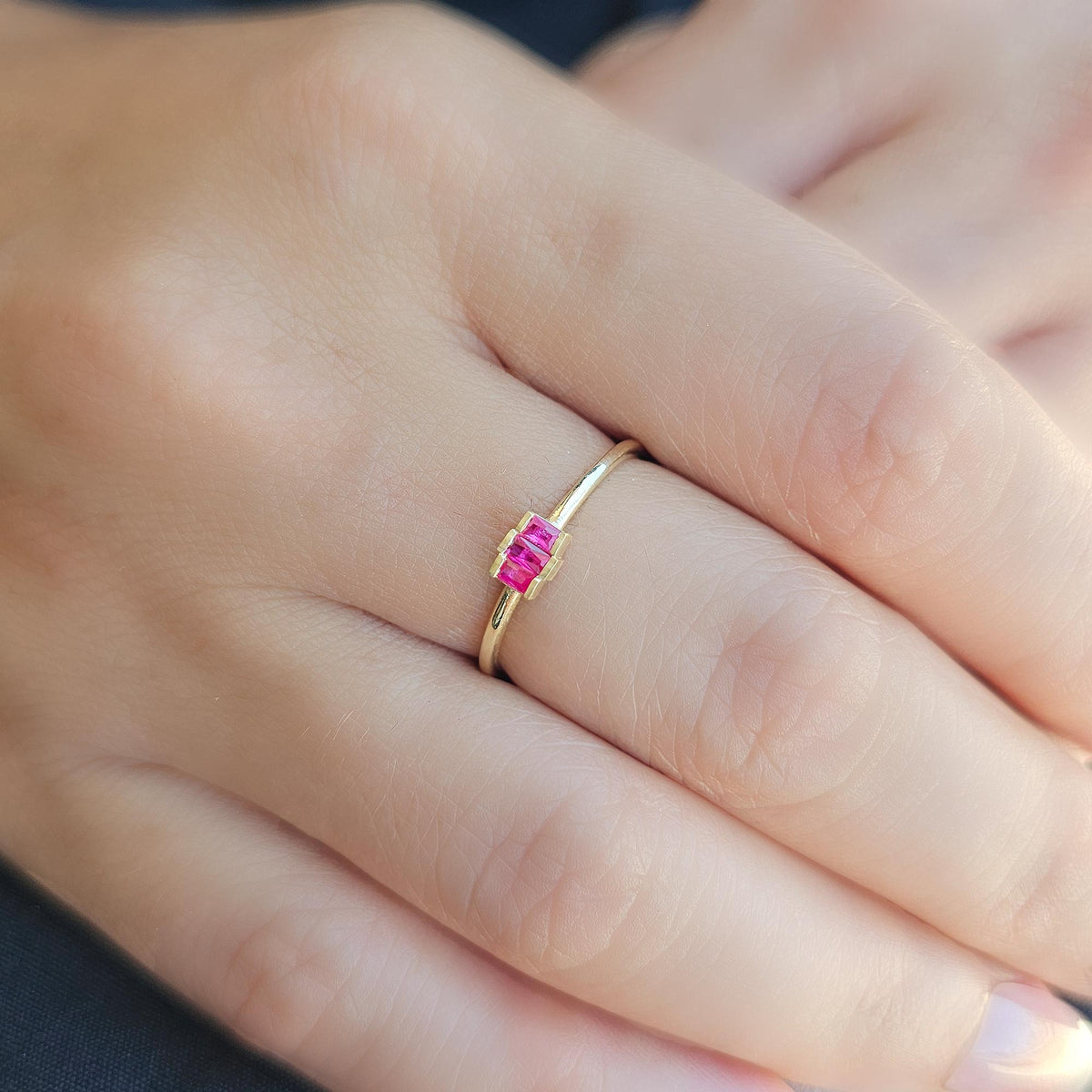 Gold red-stone three-baguette ring worn on hand
