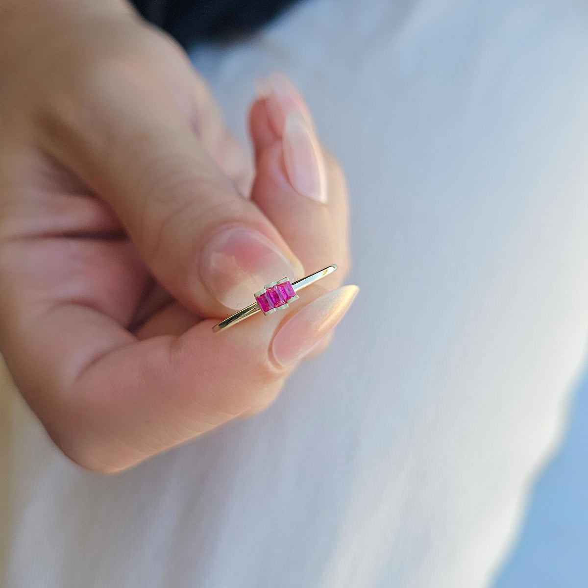 Gold red-stone three-baguette ring worn on hand, side view