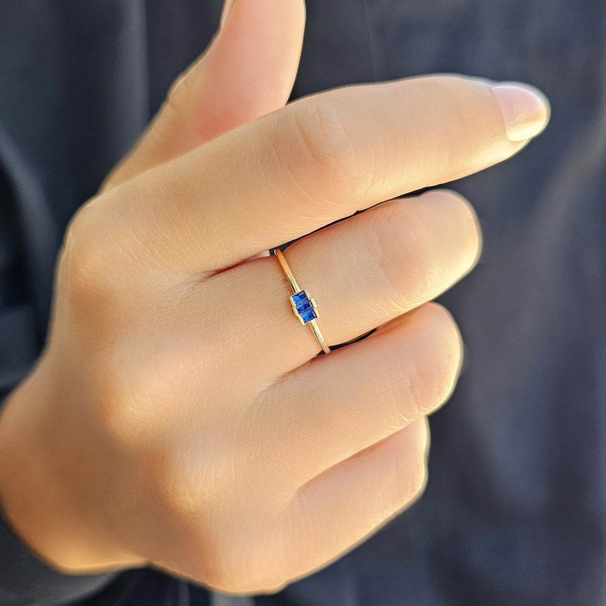 Gold blue-stone three-baguette ring worn on hand, close-up