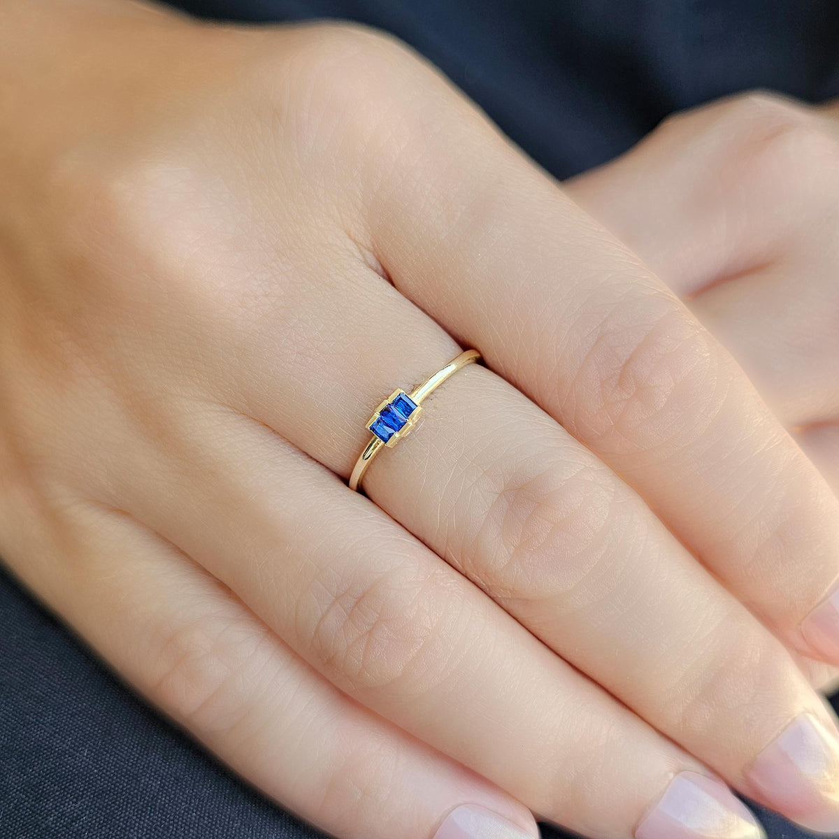 Gold blue-stone three-baguette ring worn on hand